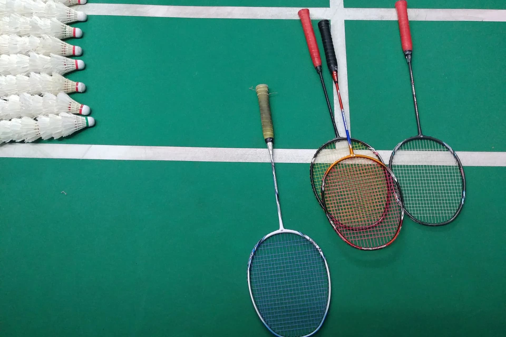 A green and white badminton court with rackets