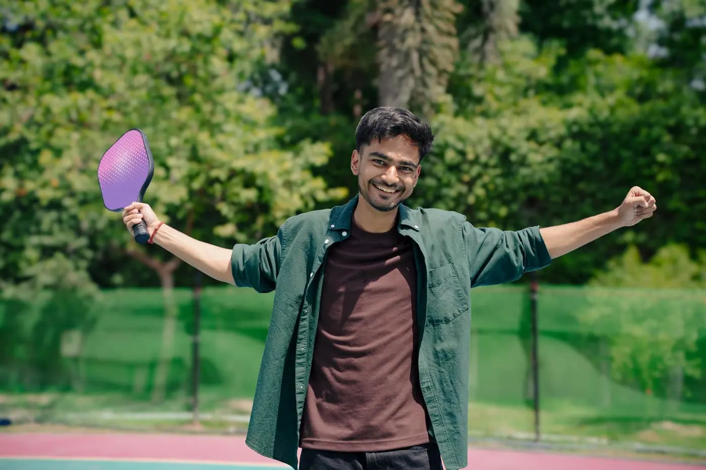 Smiling pickleball player celebrating on an outdoor court