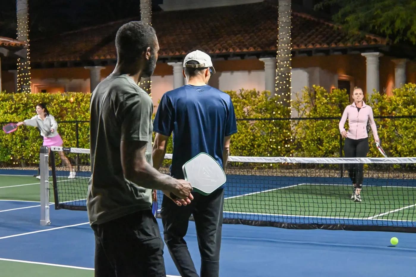 Doubles players at the net during an evening pickleball match